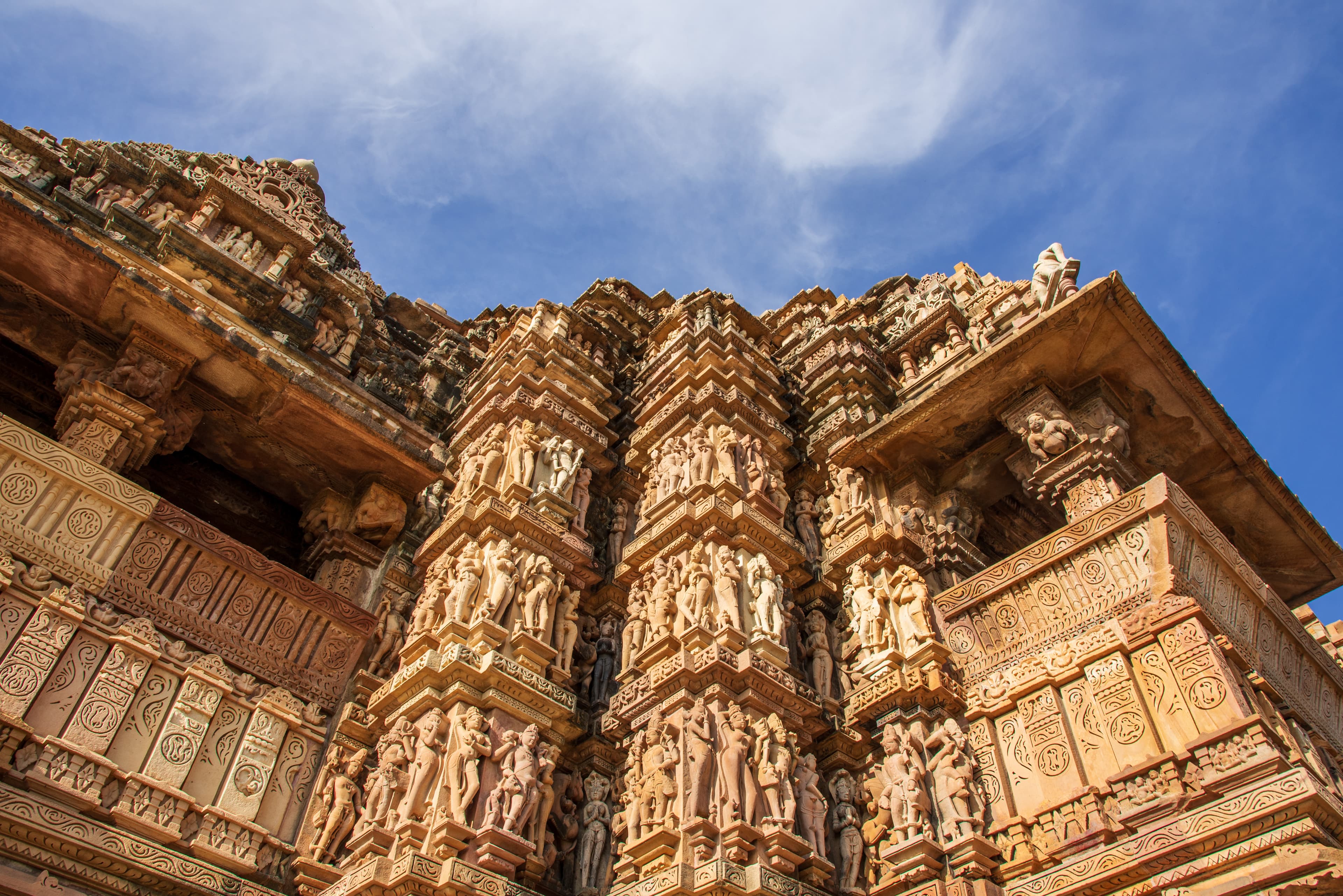 Intricate Stone Carvings of Khajuraho Temple Against a Clear Blue Sky