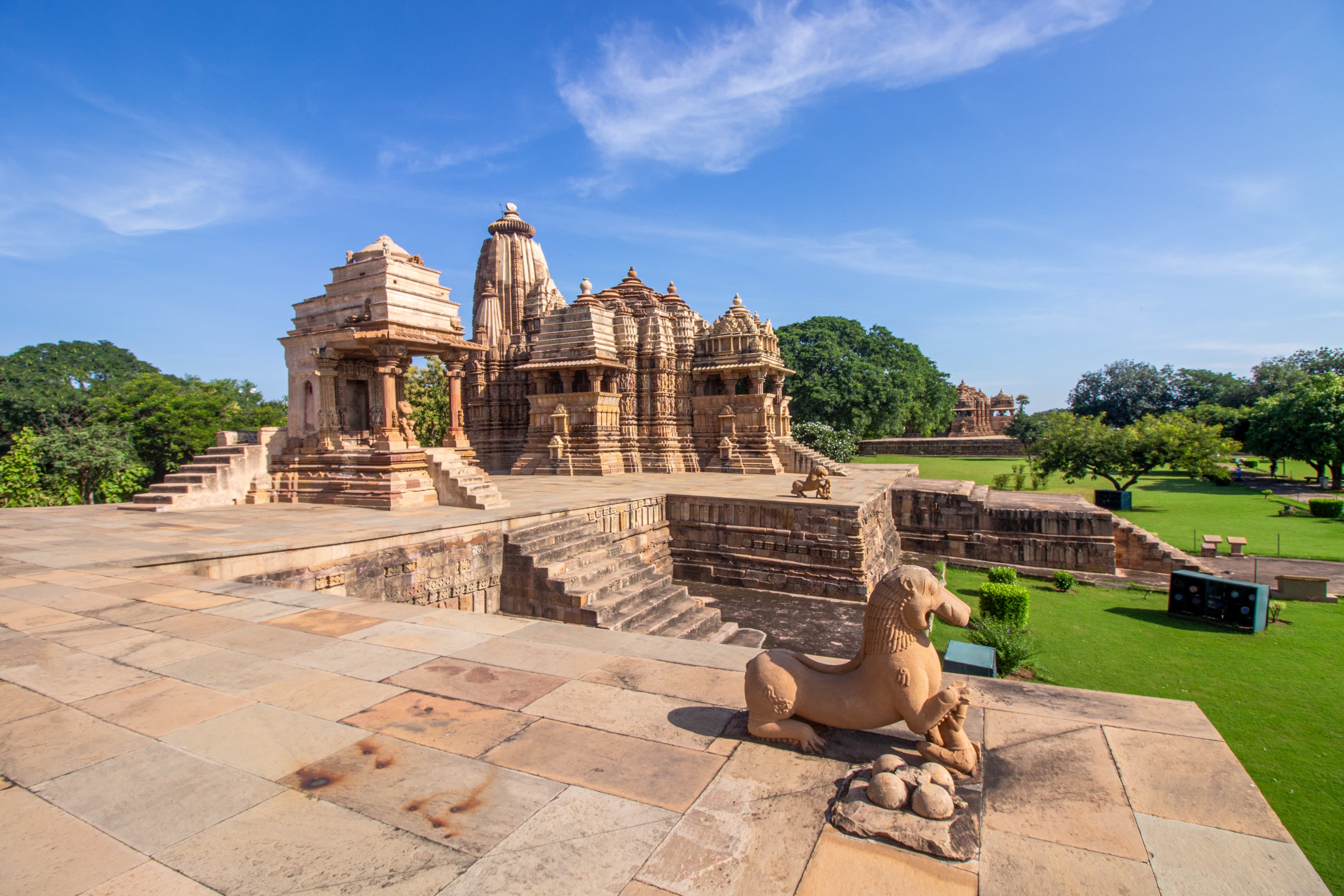 Khajuraho Temple Complex with Guardian Lion Statue Under Clear Blue Sky